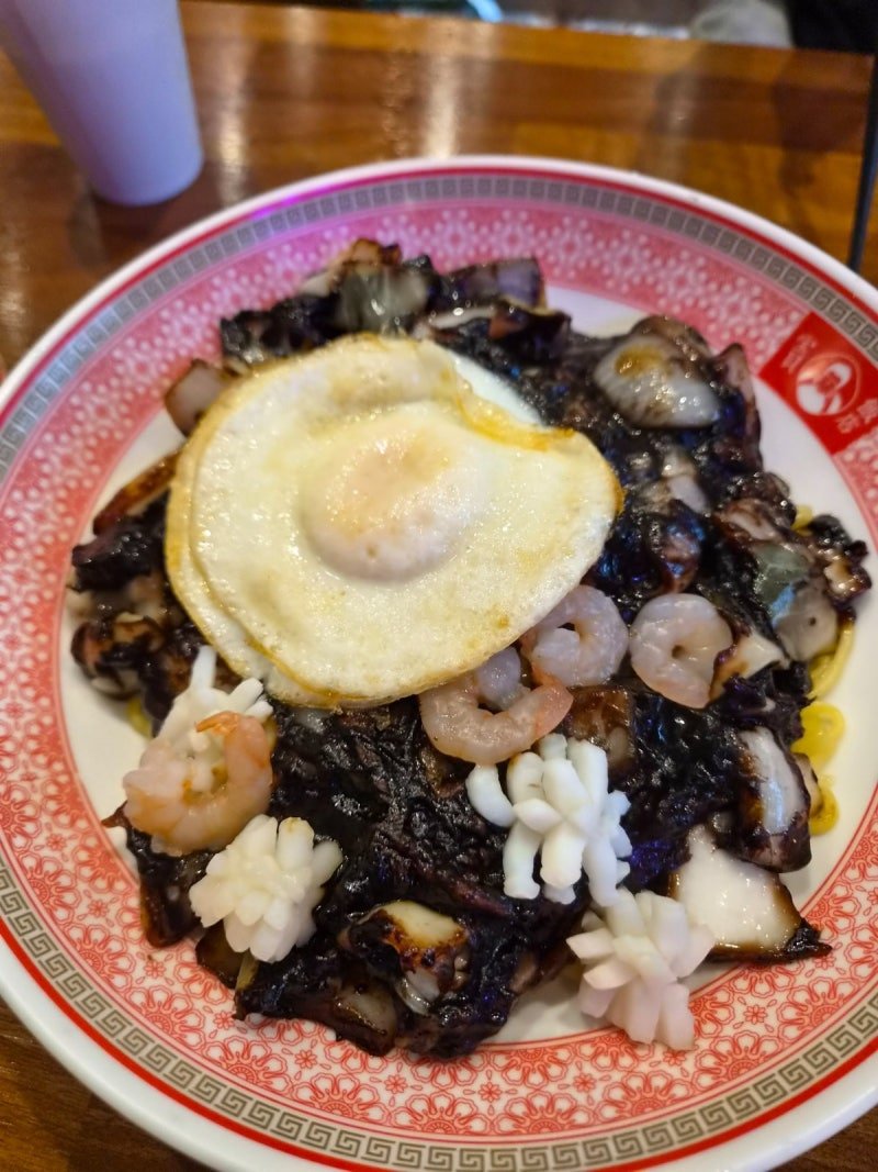 Black bean noodles topped with an egg and seafood at Bobae Banjeom