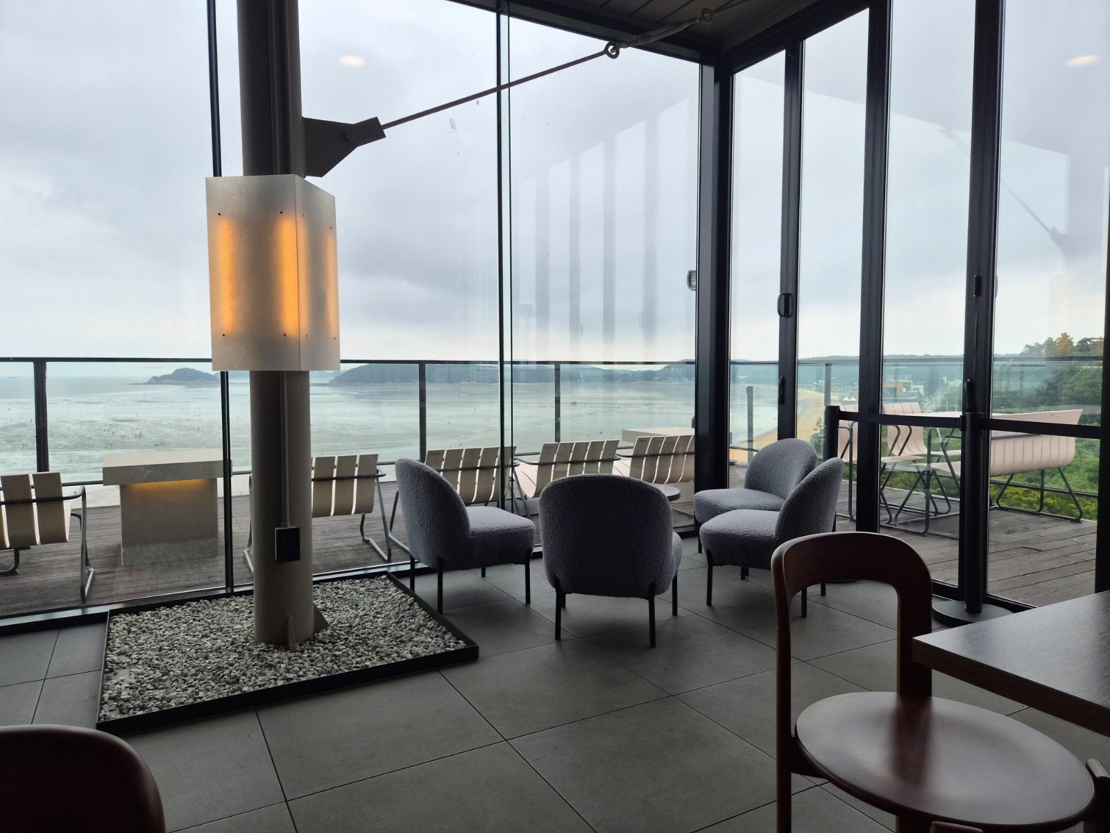 Empty lounge chairs facing the sea through Emcliff café’s windows