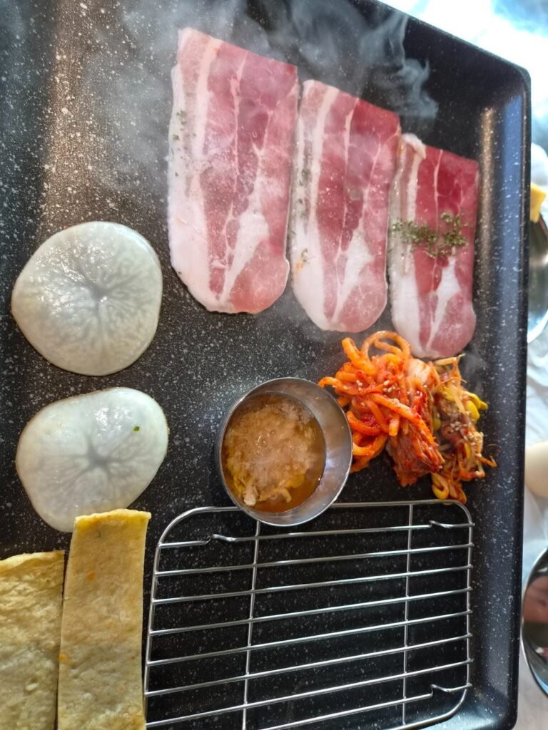 Pork belly, kimchi, potatoes and fish cake on a grill at Naengsamdo
