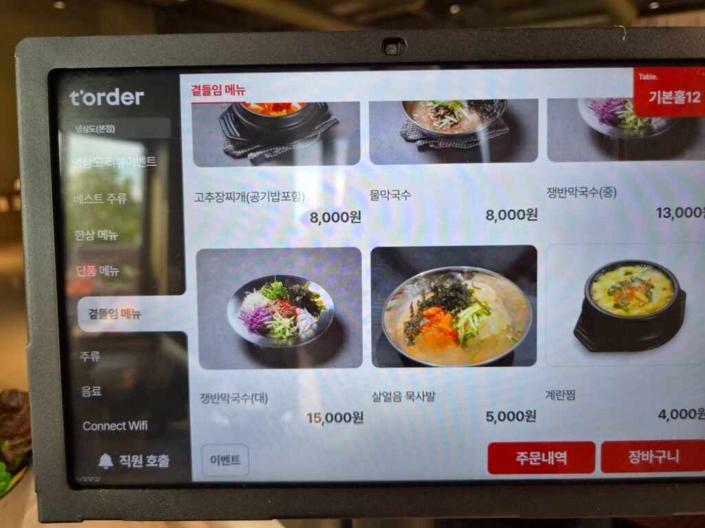Table ordering tablet at Naengsamdo showing side dishes: stew, cold noodles, acorn jelly soup and steamed egg with prices