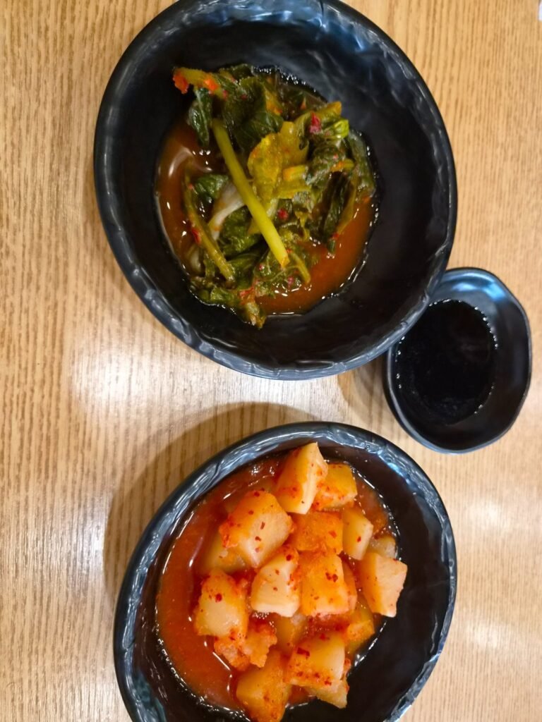 Side dishes at Unseook: young summer radish kimchi and diced radish kkakdugi in black bowls