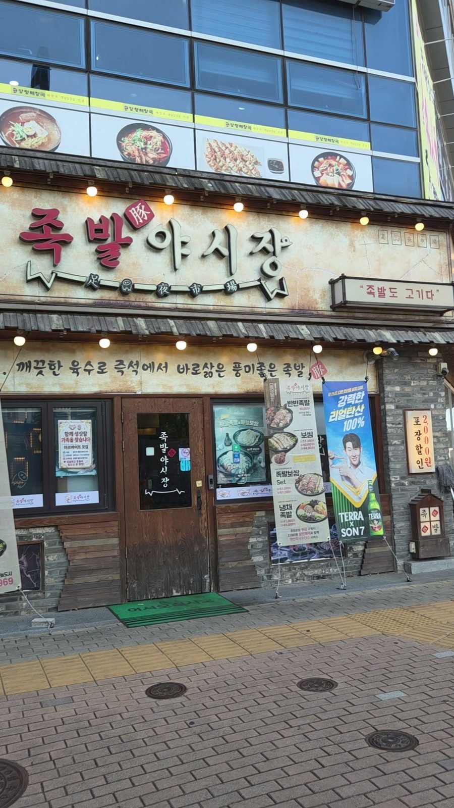 Jokbal Yasijang storefront on the ground floor of a building in Haneul City, string lights along the sign