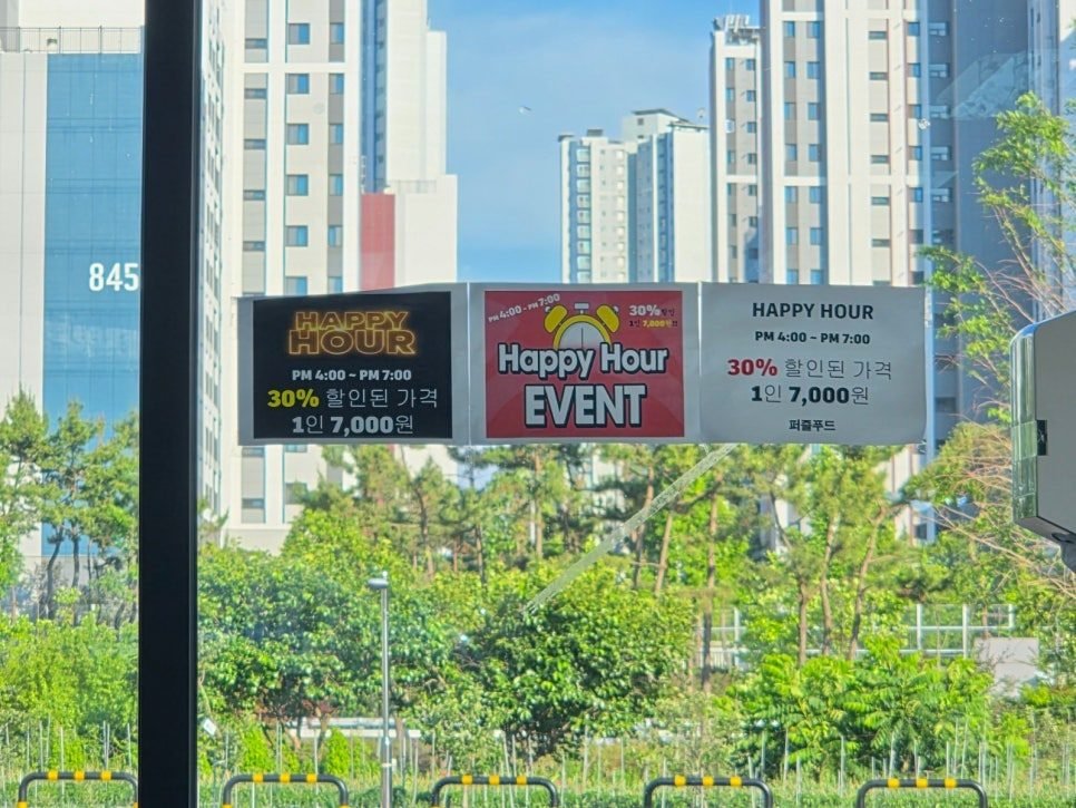 Roadside banner reading HAPPY HOUR PM 4:00 - PM 7:00, 30% 할인된 가격, 1인 7,000원, 퍼즐푸드