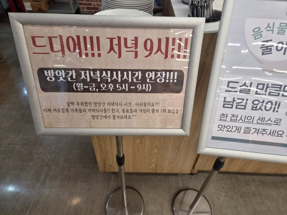 A framed notice inside Bangatgan reading 드디어 저녁 9시 and 방앗간 저녁식사시간 연장, with the hours 월~금, 오후 5시 ~ 9시.