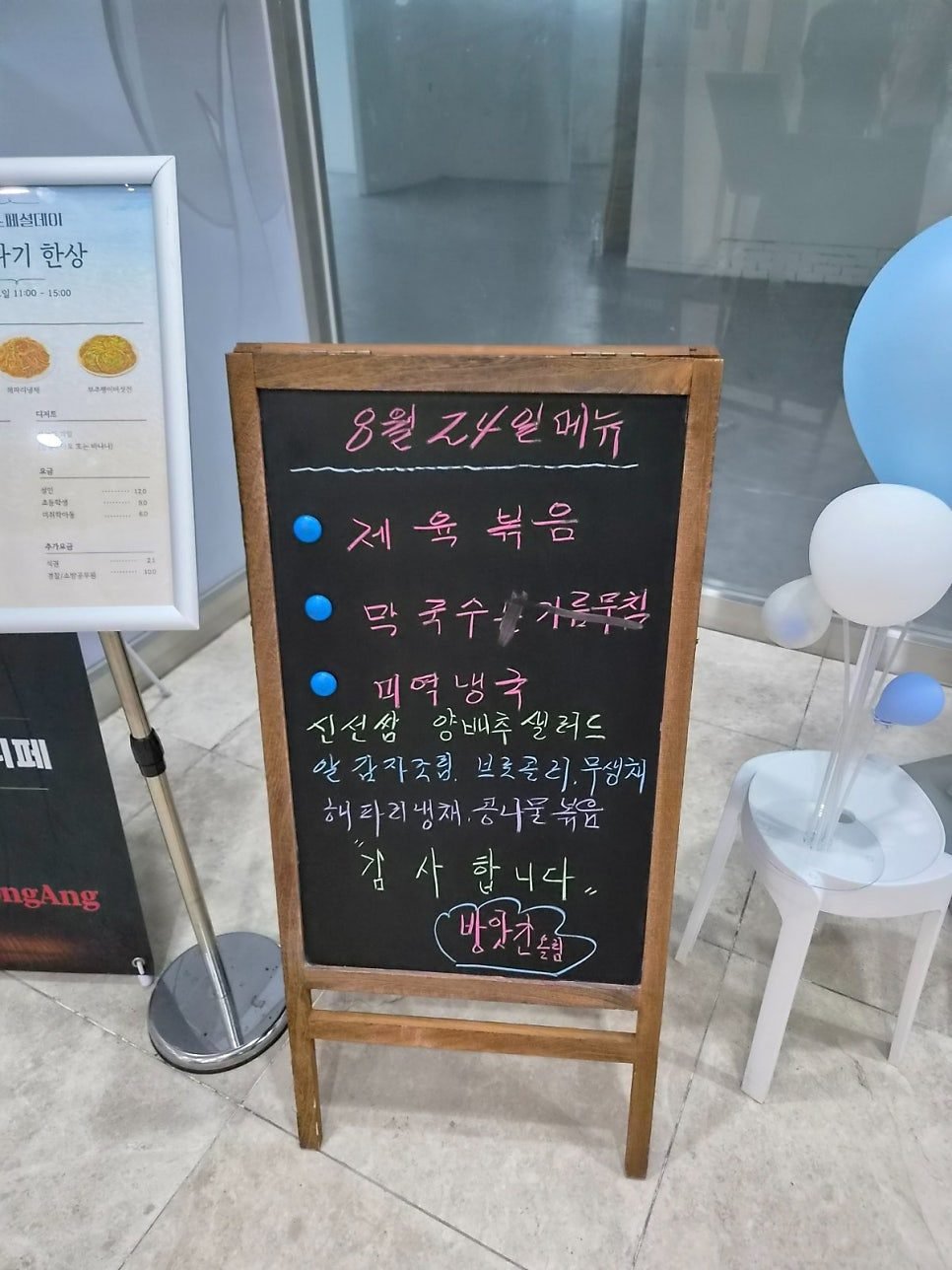 A chalkboard at the entrance headed 8월 24일 메뉴, listing 제육볶음, 막국수 and 미역냉국 as the day's main dishes.