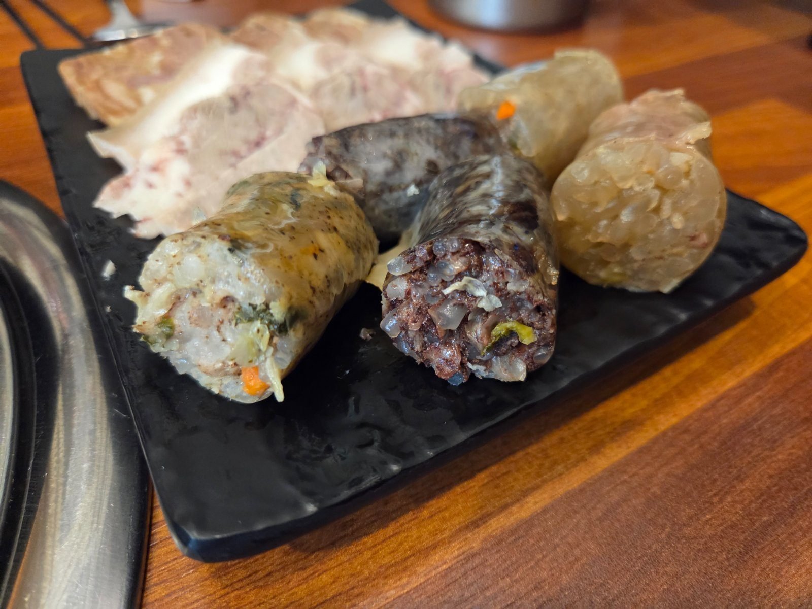 Plate of sliced head-meat pyeonyuk with white vegetable sundae and dark chal-sundae