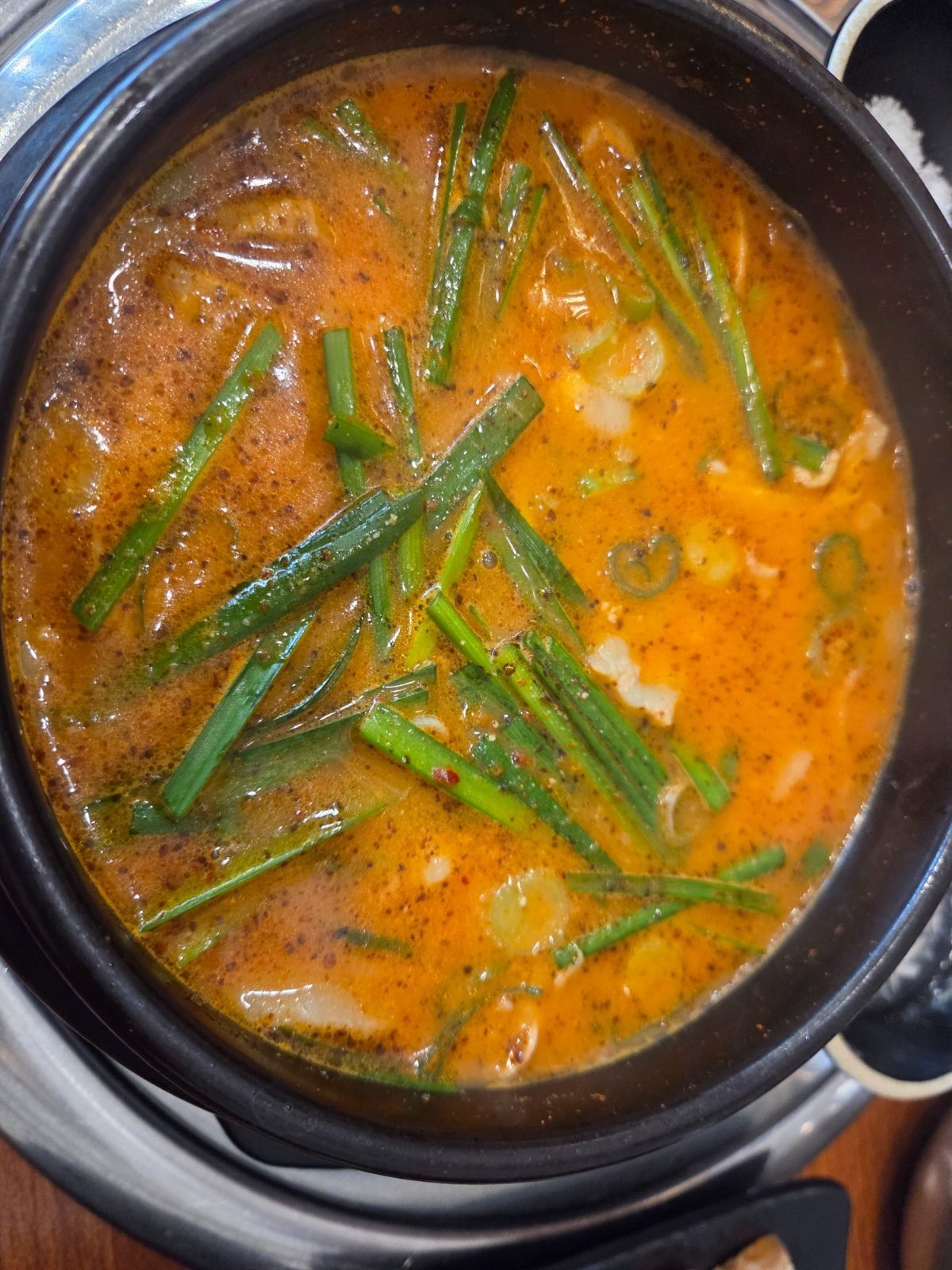 The spicy eolkeun version of the hangjeong pork soup, red broth heaped with chives