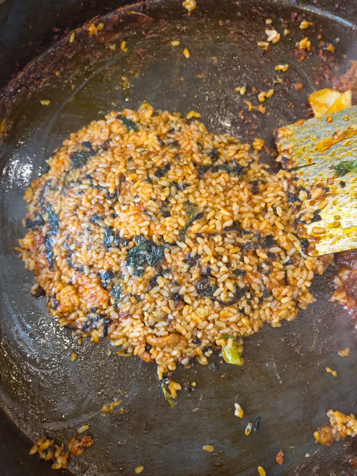 Fried rice pressed flat on the griddle, orange with leftover dak-galbi sauce and flecked with dried seaweed, a metal spatula at the edge