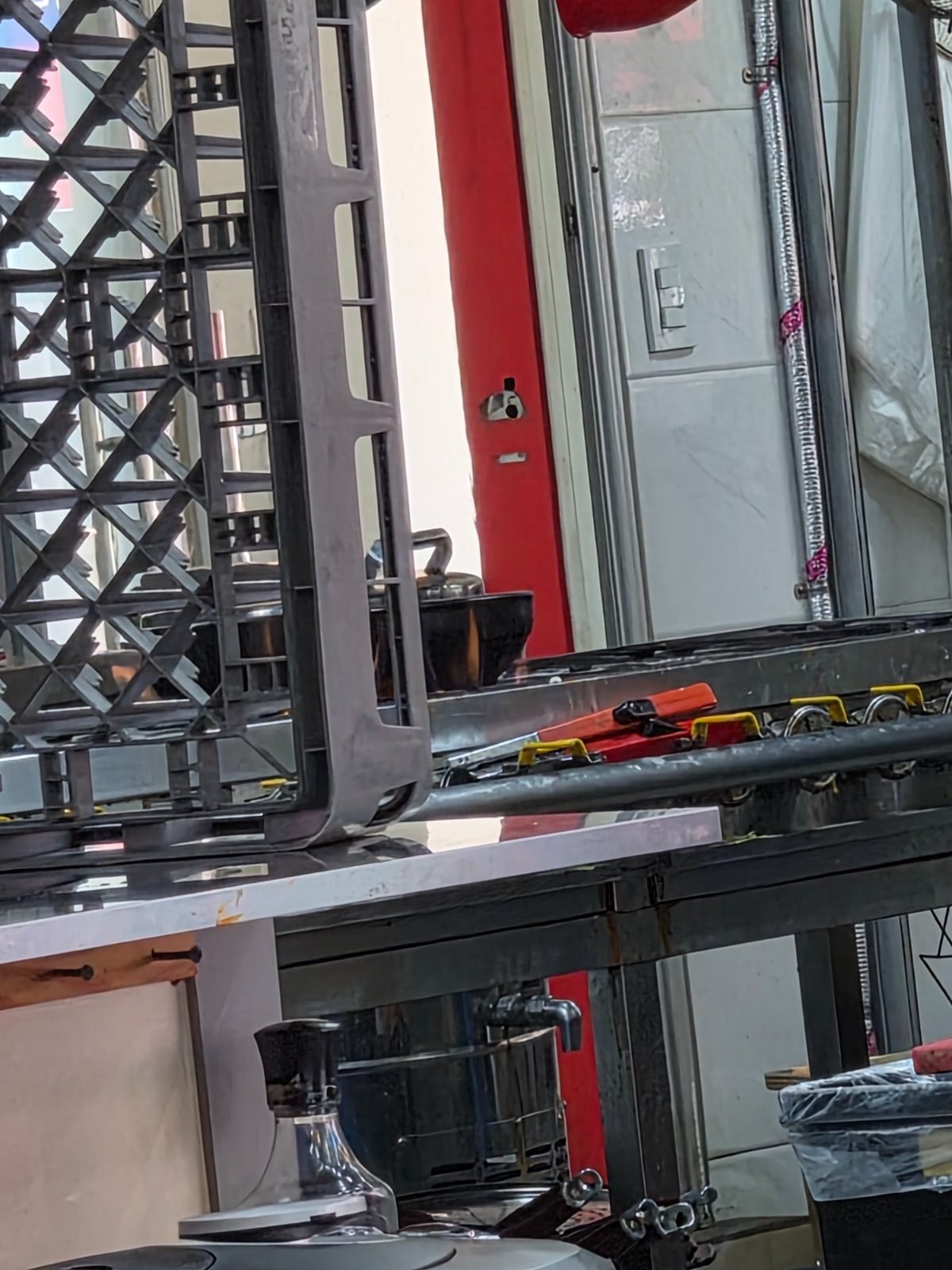 Self service station with stacked dish racks, a water urn and cutlery bins on a steel counter