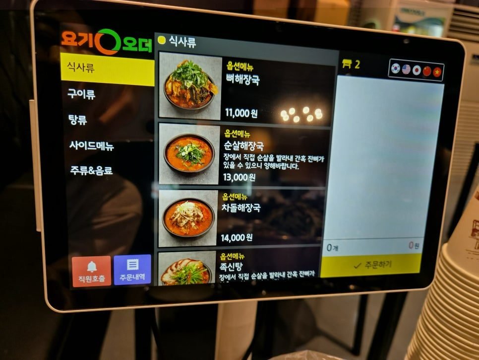 The ordering tablet at the table, meals tab open, showing ppyeo haejangguk at 11,000 won, boneless haejangguk at 13,000 won and brisket haejangguk at 14,000 won, each with a photo.
