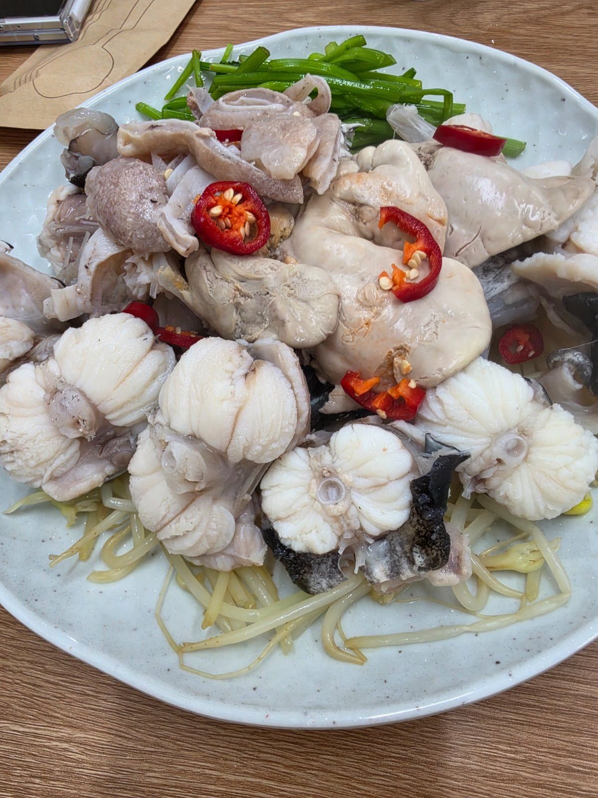 Platter of poached monkfish with skin, liver and sliced chilli on a bed of bean sprouts