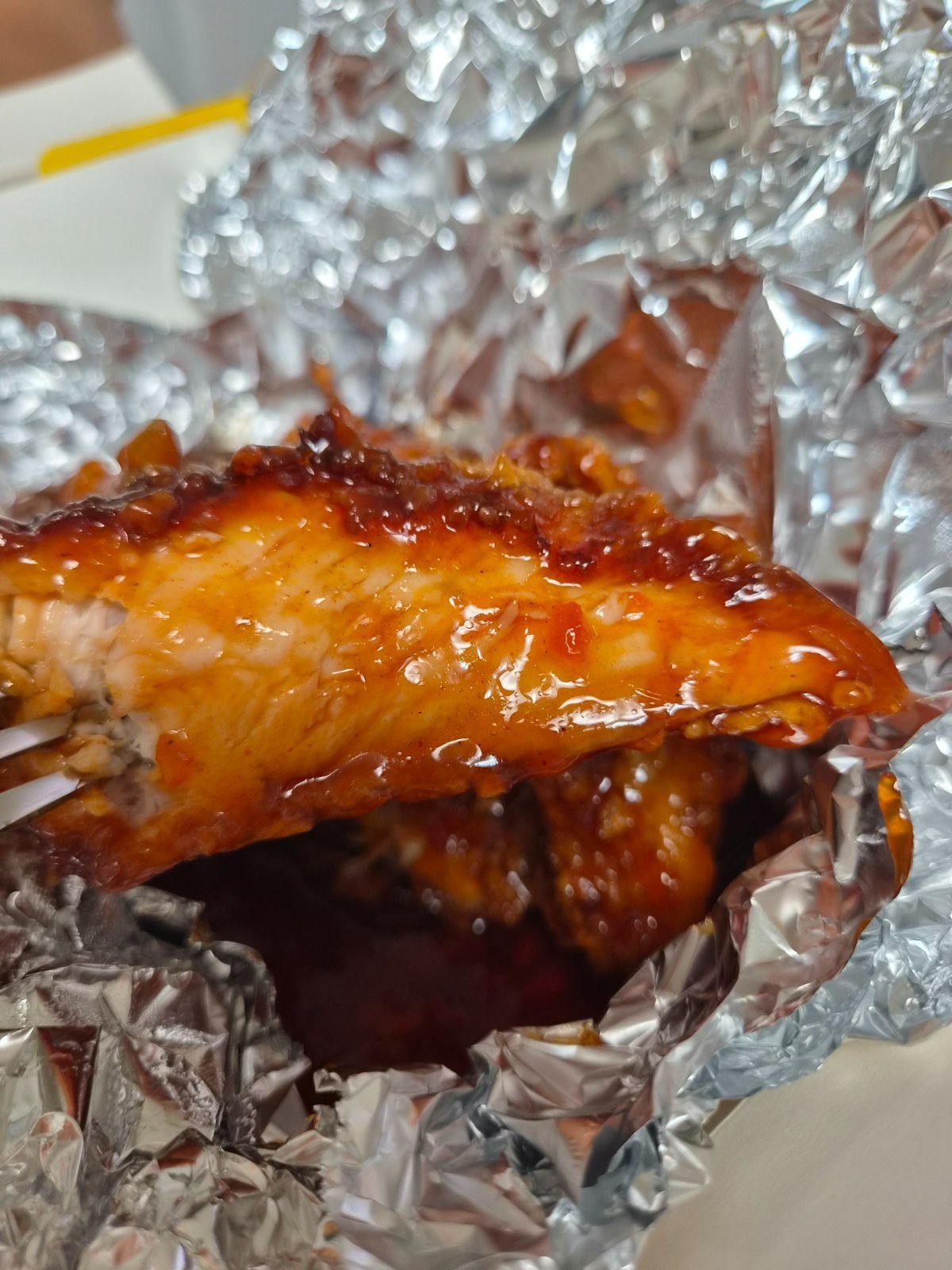 Close-up of a seasoned chicken piece coated in glossy red sauce