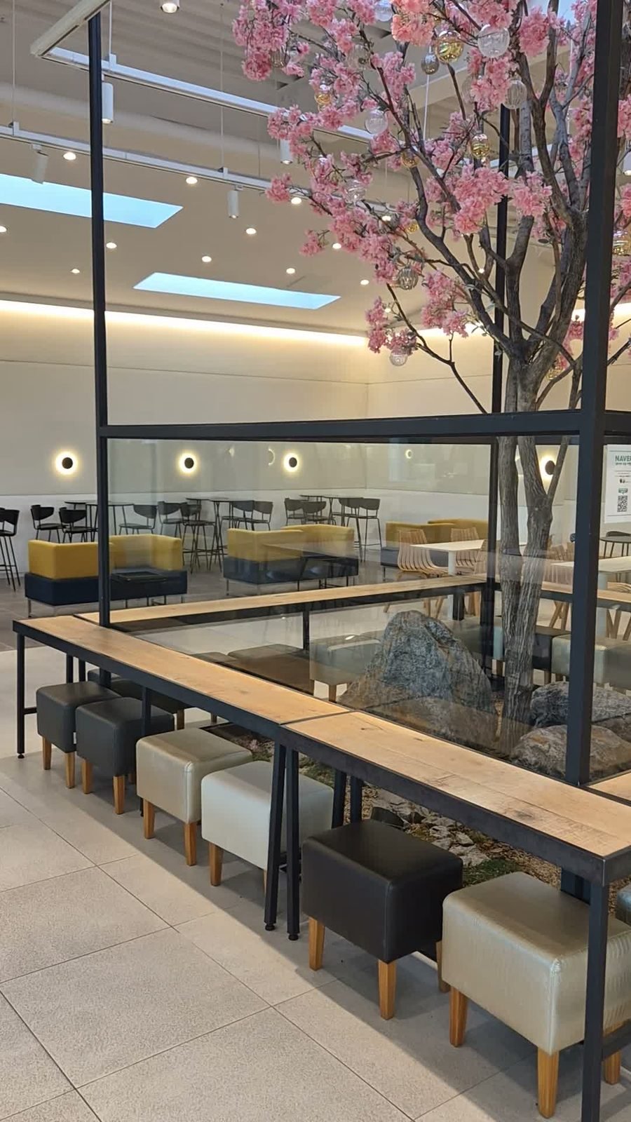 Large cafe interior with skylights, an indoor rock garden under glass and a cherry blossom tree