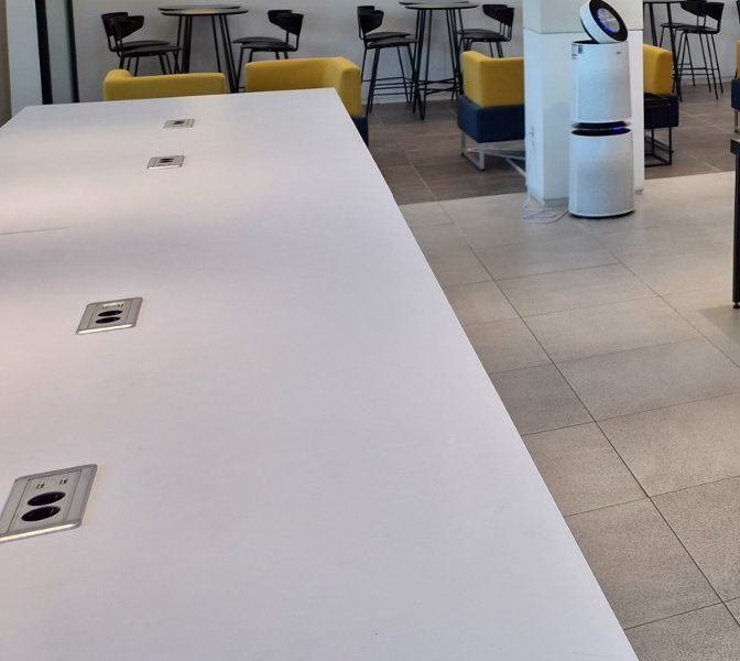 Long white communal table with power sockets and USB ports set into the surface