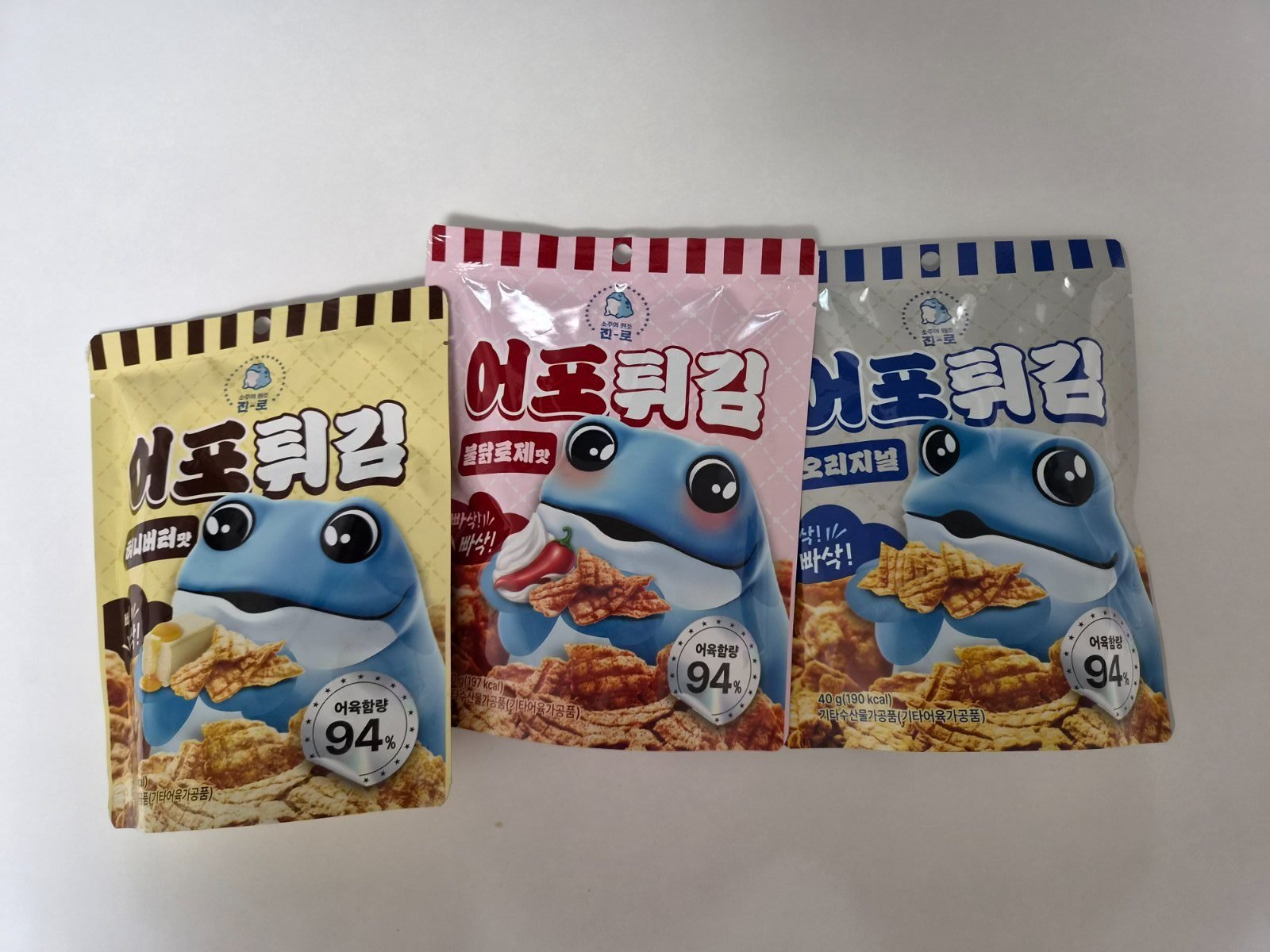 Three bags of Jinro eopo-twigim fish crisps in honey butter, buldak rose and original, each printed with a 94 percent fish content seal