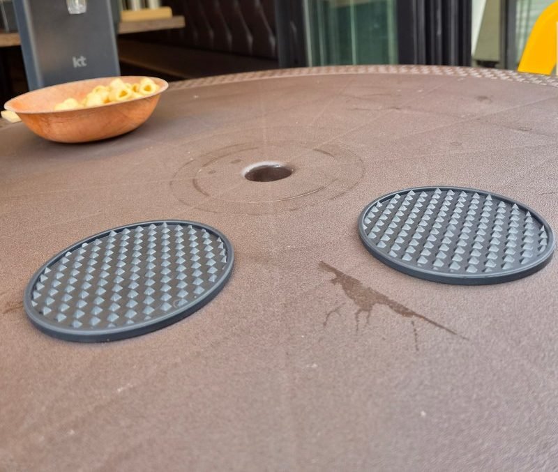 A wooden bowl of macaroni crisps on a brown outdoor table with two rubber coasters, next to a table-side ordering tablet, at Kim Boknam Beer in Yeongjong Sky City