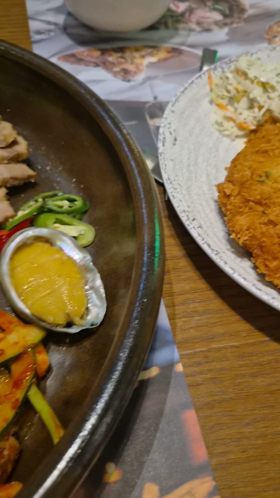 A wooden table with the pork cutlet plate and the bossam platter side by side.