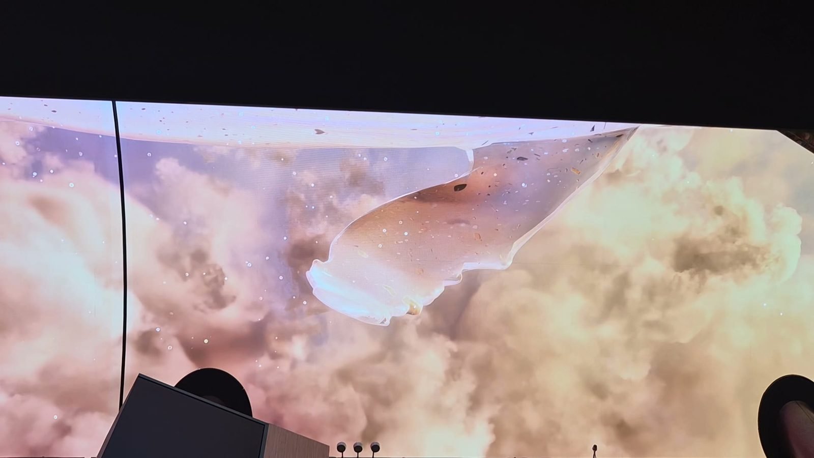 A large curved ceiling screen at Inspire Resort showing a pale whale swimming through pink clouds, seen from a table below.