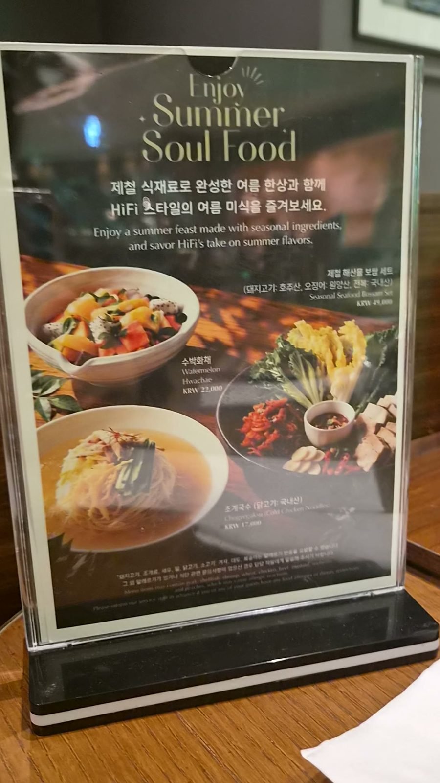 A table card headed Enjoy Summer Soul Food, listing a seasonal seafood bossam set, watermelon hwachae and cold chicken noodles with photographs and prices in Korean and English.