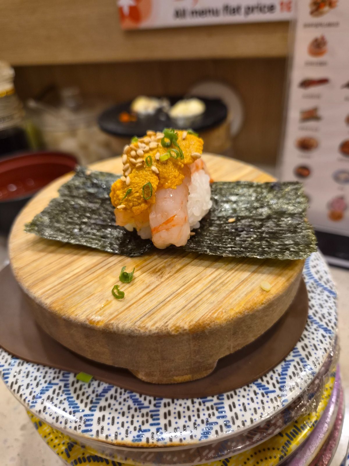 Shrimp topped with monkfish liver and served on seaweed on a small wooden stand