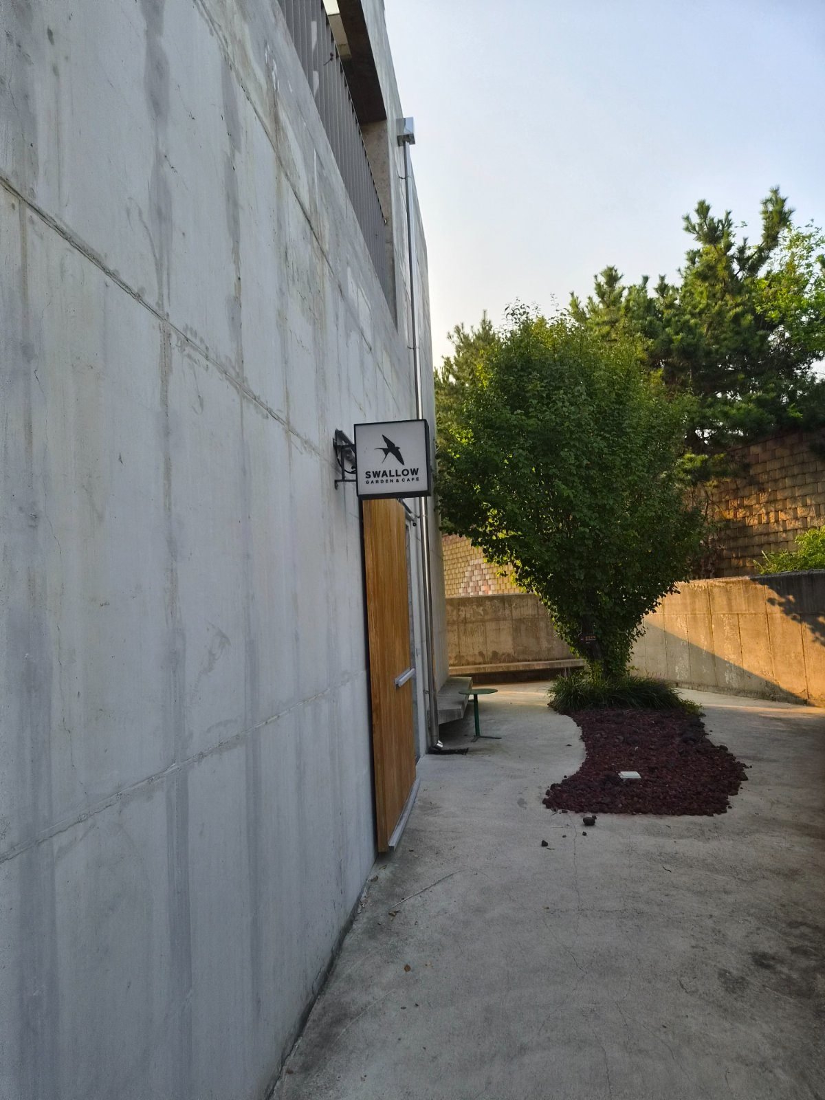 Wooden door with SWALLOW sign at the end of a concrete wall